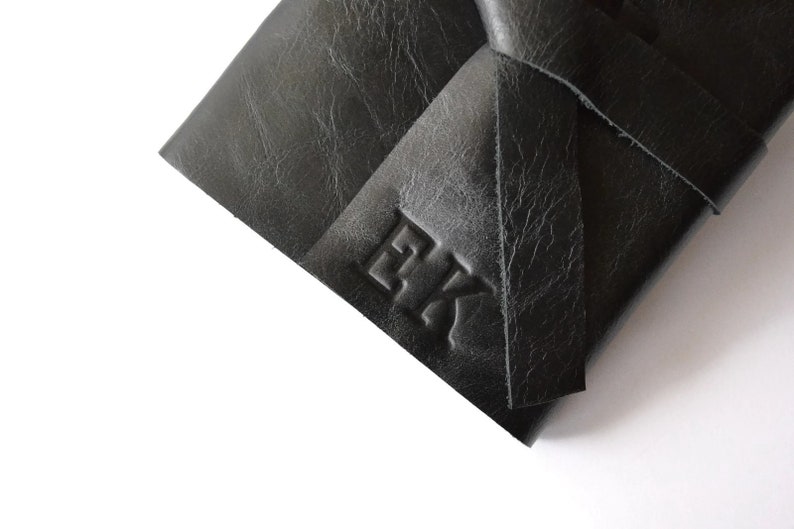 May include: Black leather journal with a knotted closure and the initials "EK" embossed on the front.