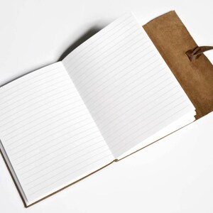 K&ouml;nnte beinhalten: Ein braunes, ledergebundenes Tagebuch mit einer leeren, linierten Seite, die aufgeschlagen ist. Das Tagebuch hat einen Lederriemenverschluss und einen braunen Lederquaste.