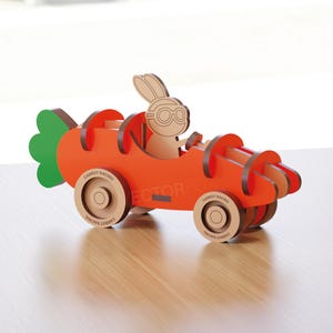Könnte beinhalten: Ein Holzspielzeugauto in Form einer Karotte, mit einem Hasenfahrer mit Brille. Das Auto ist orange mit Holzrädern und einem grünen Karottenspitze. Der Text "VECTORFOX" steht unten.