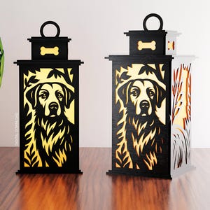 Könnte beinhalten: Zwei dekorative Laternen mit einem Hundesilhouetten-Design. Die Laternen sind schwarz mit einem goldgelben Innenraum und zeigen ein Hundeporträt. Jede Laterne hat einen Griff und einen knochenförmigen Akzent. Die Laternen stehen auf einer Holzoberfläche.