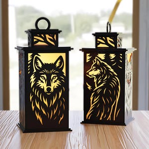 May include: Two black wooden lanterns with wolf silhouettes. The lanterns have a rectangular shape with a decorative top and a handle. The wolf design is illuminated with a warm light, creating a cozy ambiance. The lanterns are placed on a wooden surface.