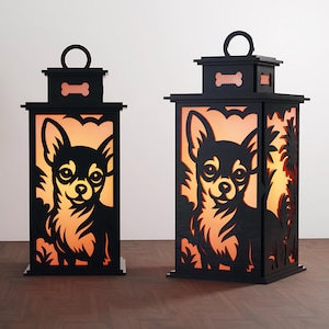 以下が含まれることがあります： 黒い木製のランタン2つ。チワワ犬のデザイン。ランタンには骨の形をした切り抜きと上部にハンドルが付いています。犬の画像が切り抜かれており、光が差し込み、温かい輝きを生み出しています。ランタンは木製の表面に置かれています。