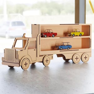May include: A wooden toy truck with three shelves, each holding a miniature car. The cars are red, yellow, and blue. The truck is made of light-colored wood and has a detailed design.