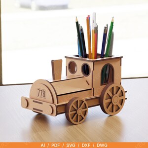 May include: A wooden train-shaped desk organizer with pencils and pens inside. The organizer is light brown with dark brown wheels and accents. The number "778" is printed on the front of the train.