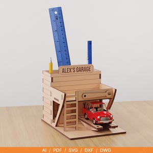 Puede incluir: Un organizador de escritorio de madera con forma de garaje, con el texto "ALEX'S GARAGE". Cuenta con un coche de juguete rojo en un elevador, una regla azul, un bolígrafo azul y un bolígrafo amarillo. El organizador es de madera marrón claro.