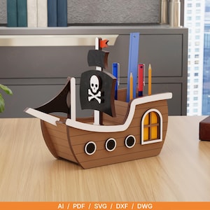 May include: A brown wooden pirate ship desk organizer featuring a black sail with a white skull and crossbones emblem, three circular portholes, a yellow-paned window, and internal compartments holding various pens, pencils, and a blue ruler.