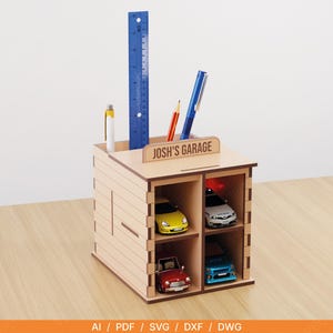 Puede incluir: Un organizador de escritorio de madera con el texto "Josh's Garage" en la parte superior. Cuenta con compartimentos para bolígrafos, lápices y una regla azul. La sección inferior tiene coches de juguete en miniatura de varios colores, incluyendo amarillo, rojo, blanco y azul.