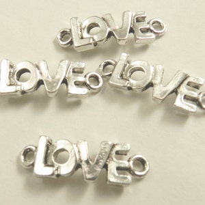May include: Four silver-toned metal charms, each spelling out the word "LOVE" in a stylized font. The charms have a loop on each end for attaching to jewelry or other crafts.