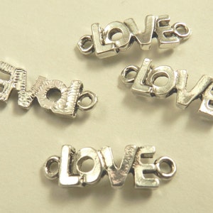 May include: Four silver-toned metal charms, each spelling out the word "LOVE" in a stylized font. The charms have a loop on each end for attaching to jewelry or other crafts.