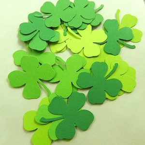 May include: A pile of green paper shamrocks, some are a lighter shade of green than others.