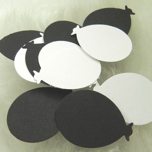 May include: A collection of black and white paper balloons. The balloons are cut out in the shape of a balloon with a rounded bottom and a pointed top.