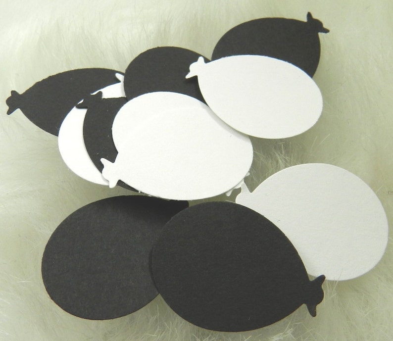 May include: A collection of black and white paper balloons. The balloons are cut out in the shape of a balloon with a rounded bottom and a pointed top.