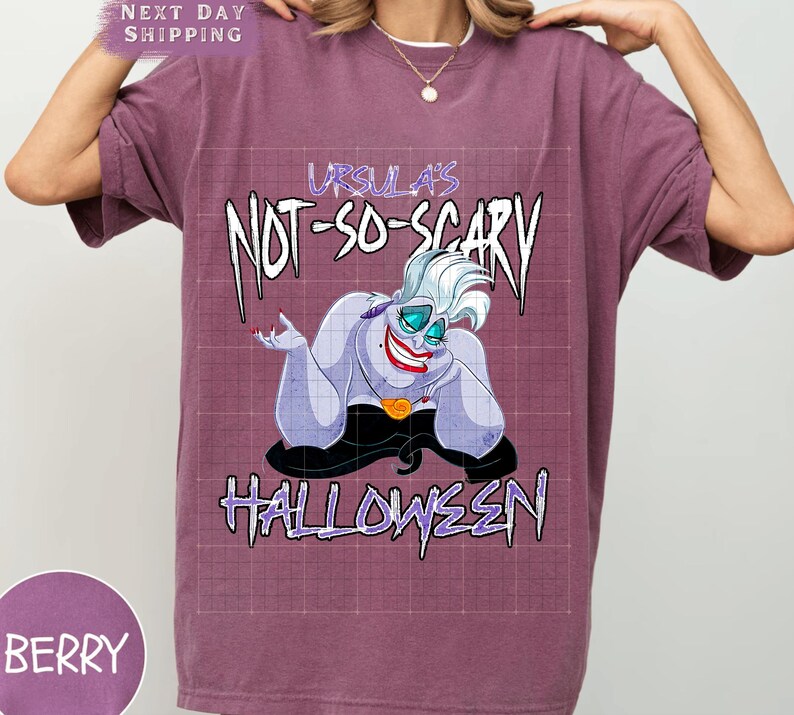 May include: Berry-colored t-shirt featuring a graphic of Ursula from The Little Mermaid. The design includes the text "Ursula's Not-So-Scary Halloween" in a spooky font, with Ursula's image in the center.