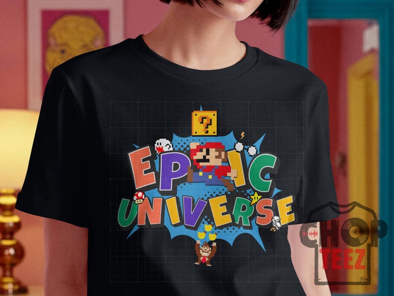 May include: Black t-shirt featuring a colorful graphic design with the words "EPIC UNIVERSE" in a comic book style. The design includes pixelated characters and elements from a popular video game.