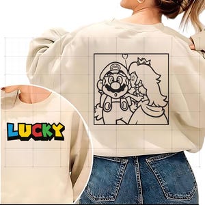 May include: Cream-colored sweatshirt with the word "LUCKY" in blue, yellow, green, and red block letters. The back features a black and white graphic of Mario and Princess Peach kissing inside a square.