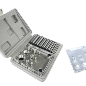 May include: A jewelry making tool set with a gray plastic case, a metal plate with various sized circular punches, and a clear acrylic plate with holes. A small silver wrench is also included.