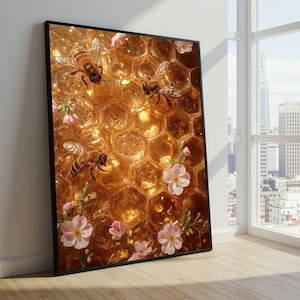 Op de afbeelding: Een ingelijste kunstdruk met een close-up van een honingraat met drie bijen en delicate roze bloemen. Het kunstwerk heeft een warm, goudkleurig kleurenpalet, waarbij de vleugels van de bijen en de honingraatcellen het licht vangen. De print zit in een zwarte lijst.