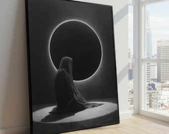 May include: Black and white framed art print. The artwork features a figure in a hooded cloak seated in front of a large, dark circle with a bright halo. The print is leaning against a white wall next to a window with a city view.
