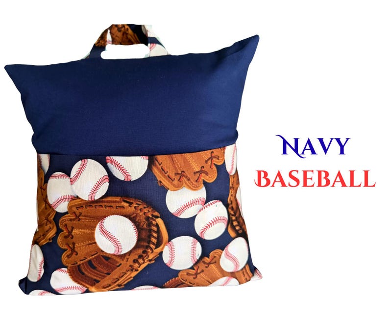 Puede incluir: Coj&iacute;n de lectura azul marino con dise&ntilde;o de b&eacute;isbol. El coj&iacute;n tiene una parte superior azul marino y una parte inferior estampada con pelotas y guantes de b&eacute;isbol. El texto "NAVY BASEBALL" es visible.