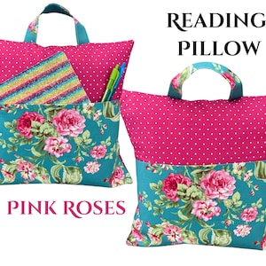 Puede incluir: Una almohada de lectura rosa con asa, con la parte superior de lunares y la parte inferior con estampado floral. La almohada tiene un bolsillo con un patr&oacute;n de rayas arco&iacute;ris y contiene bol&iacute;grafos. Se muestra el texto "Reading Pillow" y "Pink Roses".