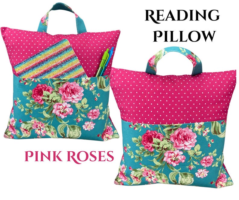 Puede incluir: Una almohada de lectura rosa con asa, con la parte superior de lunares y la parte inferior con estampado floral. La almohada tiene un bolsillo con un patr&oacute;n de rayas arco&iacute;ris y contiene bol&iacute;grafos. Se muestra el texto "Reading Pillow" y "Pink Roses".