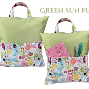 Puede incluir: Dos cojines de lectura verde claro con un bolsillo colorido con un dise&ntilde;o tropical. Los cojines tienen asas con un estampado floral. Un coj&iacute;n tiene un cuaderno rosa y bol&iacute;grafos en el bolsillo. El texto "GREEN SUN FUN" est&aacute; encima de los cojines.