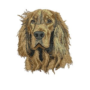 May include: A detailed embroidery of a dog's head, featuring a brown and black color scheme. The dog has long, flowing fur and a focused expression. The artwork is set against a plain white background, highlighting the intricate details of the design.