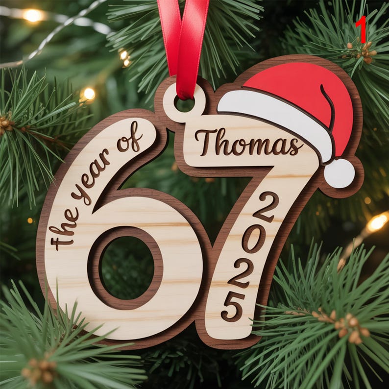 May include: A wooden Christmas ornament with the text "the year of" and "67 2025". The ornament has a Santa hat design and the name "Thomas". It is hanging from a red ribbon.