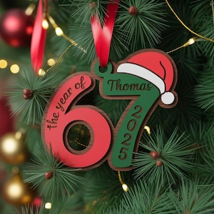 May include: A personalized Christmas ornament with the text "the year of 67" and "2025". The ornament features a red number 67, green number 2025, and a Santa hat. The name "Thomas" is also displayed on the ornament.
