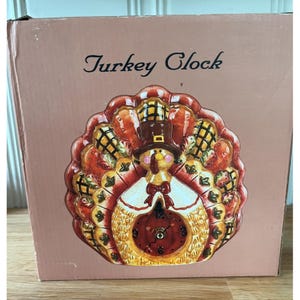 May include: A ceramic turkey clock in a box. The clock is shaped like a turkey with a brown top hat, a white bib, and a red bow tie. The clock face is red with black numbers. The box reads "Turkey Clock".