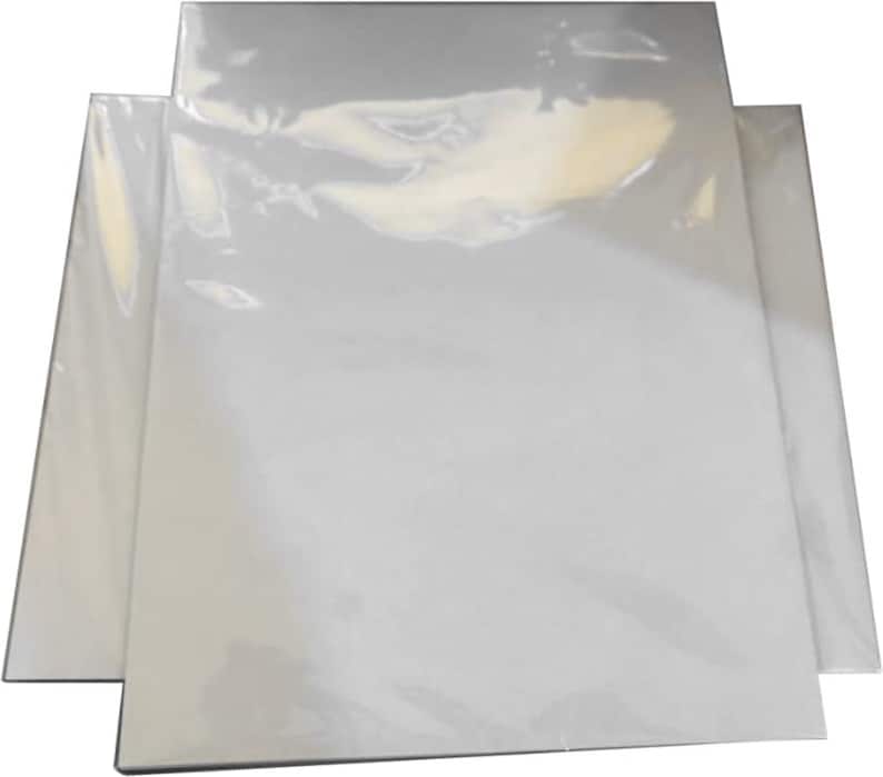 May include: A stack of white canvas panels, wrapped in clear plastic, are displayed. The panels are rectangular and appear unused, ready for artistic projects. The plastic wrap gives a glossy appearance. The panels are likely for painting or mixed media.
