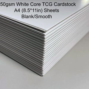Könnte beinhalten: Ein Stapel weißer Kartonblätter. Der Text auf dem Bild lautet: 350gsm White Core TCG Cardstock, A4 (21,6 x 27,9 cm) Sheets, Blank/Smooth. Die Blätter sind leer und glatt.
