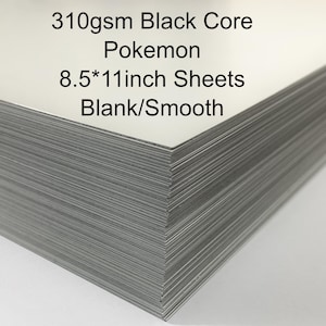 May include: A stack of blank, smooth 8.5 x 11 inch sheets with a black core. The text on the top sheet reads "310gsm Black Core Pokemon Blank/Smooth."