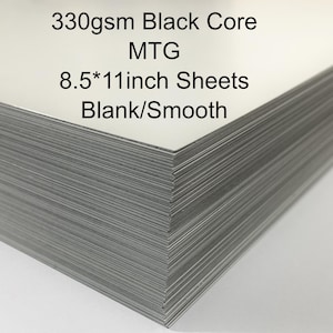 May include: A stack of blank white 8.5 x 11 inch sheets with a black core. The text on the top sheet reads "330gsm Black Core MTG 8.5*11inch Sheets Blank/Smooth."