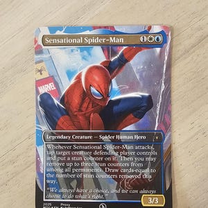 May include: A Sensational Spider-Man trading card with the superhero in action. The card has a red and blue design, with the Marvel logo. Text details the creature type, abilities, and a quote. The card's power and toughness are 3/3.