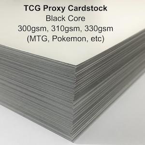 May include: A stack of TCG Proxy Cardstock with a black core. The cardstock is labeled with the text "TCG Proxy Cardstock Black Core 300gsm, 310gsm, 330gsm (MTG, Pokemon, etc)". The cards have a white surface and gray edges.
