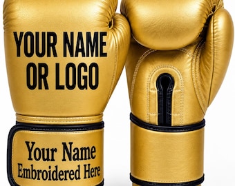 Op de afbeelding: Een paar metallic gouden bokshandschoenen met zwarte randen. De linkerhandschoen is voorzien van de zwarte tekst "YOUR NAME OR LOGO" en de polsband toont de zwarte tekst "Your Name Embroidered Here". De rechterhandschoen toont de handpalm.
