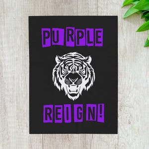 Könnte beinhalten: Schwarze rechteckige Grafik mit den Worten "PURPLE REIGN!" in lilafarbenen Blockbuchstaben. Eine weiße Tigerkopf-Grafik ist zwischen den Worten zentriert. Der Tiger brüllt mit offenem Maul.