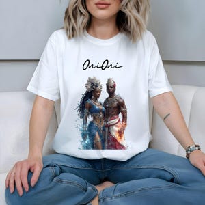 May include: White t-shirt featuring a digital art print of a man and woman in ornate attire. The woman is in blue, the man in red and white. The shirt has the word "Oni Oni" in black script.