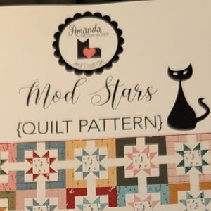 May include: A Mod Stars quilt pattern booklet featuring a grid of multi-colored star blocks in shades of red, blue, yellow, pink, and green. The cover displays the title, a black cat logo, and text stating Quilt Size 60" x 72", Block Size 12", and 10" Precut Square Friendly.