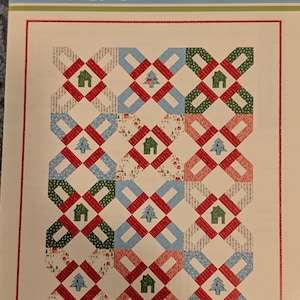 May include: A quilt pattern titled Cookie-Cutter Quilt Pattern featuring a grid of blocks with alternating house and tree motifs. The design uses a variety of fabrics in red, green, blue, and white, arranged in a repeating geometric pattern.