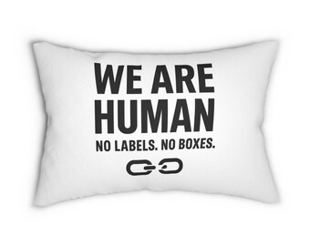 Puede incluir: Cojín rectangular blanco con el texto negro "WE ARE HUMAN", seguido de "NO LABELS. NO BOXES." y un símbolo de eslabón de cadena. Un artículo de decoración para el hogar.