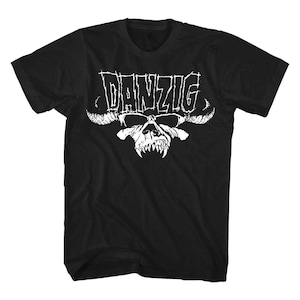 Puede incluir: Camiseta negra con el nombre de la banda "DANZIG" en blanco, con una fuente desgastada, sobre un gráfico de calavera blanca con cuernos y dientes afilados. La camiseta es de cuello redondo.