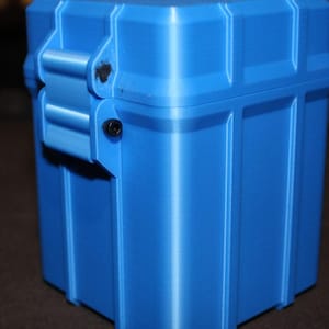 May include: A bright blue, rectangular storage container with a hinged lid and a secure latch. The box has vertical and horizontal ridges, giving it a textured appearance. The container is made of a solid, durable material.