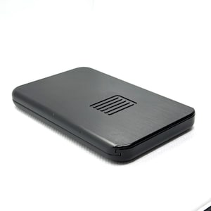 Puede incluir: Un dispositivo rectangular negro con una textura de metal cepillado y una serie de líneas paralelas cerca de la parte superior. El dispositivo tiene esquinas redondeadas y un diseño elegante y moderno, sobre un fondo blanco.