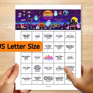 Op de afbeelding: Een Halloween-bingospel met een kleurrijk jaren 80-ontwerp. Het spel bevat songtitels als "Thriller" en "Nightmare on Street". De tekst "US Letter Size" staat op de afbeelding. Het spel wordt door twee handen vastgehouden.
