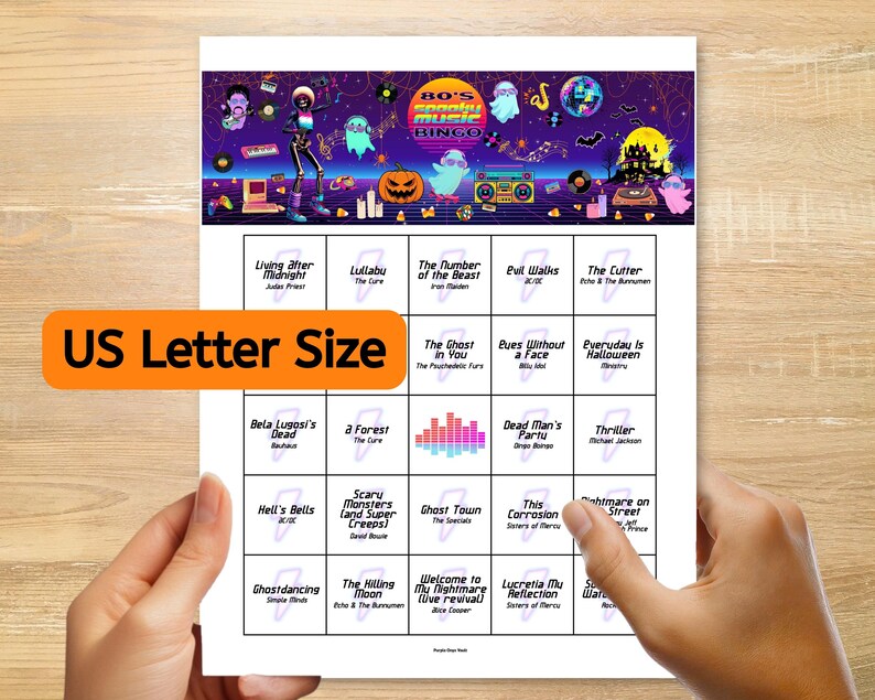 Op de afbeelding: Een Halloween-bingospel met een kleurrijk jaren 80-ontwerp. Het spel bevat songtitels als "Thriller" en "Nightmare on Street". De tekst "US Letter Size" staat op de afbeelding. Het spel wordt door twee handen vastgehouden.