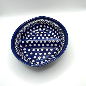Puede incluir: Un plato de cerámica azul con un interior dividido. El plato presenta un patrón de puntos blancos y formas geométricas. El borde es de un azul más oscuro y el plato tiene forma ovalada.