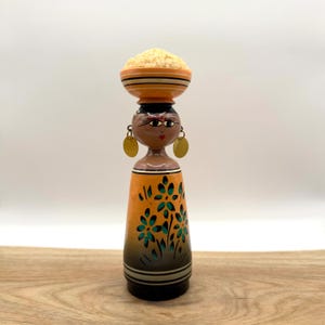 May include: A white ceramic mug with a black handle and the text "But First, Coffee" in a bold, black font. The mug sits on a white surface, showcasing its clean design.