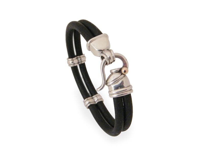 K&ouml;nnte beinhalten: Ein schwarzes Lederarmband mit einem silbernen Verschluss und einem goldenen Akzent. Das Armband ist doppelschichtig und hat einen Hakenverschluss.